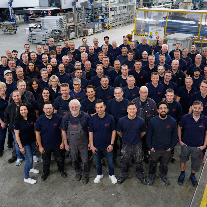 Gruppenbild alle Mitarbeiter von Kiesling Kühlfahrzeuge in der Produktionshalle